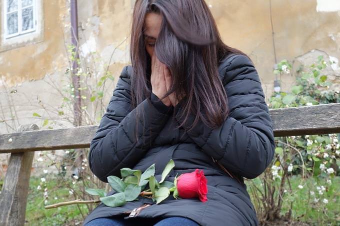 A woman crying with a rose on her lap