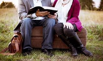 A man holding a book sitting next to a woman