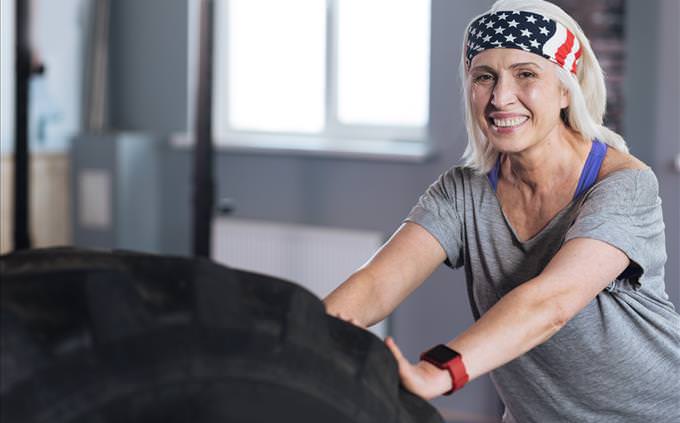 senior woman pushing tire at gym