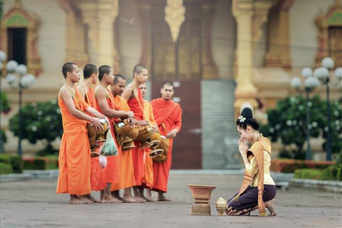 Asian woman kneeling before monks