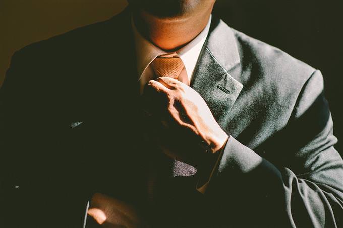 A man in a suit ties a tie