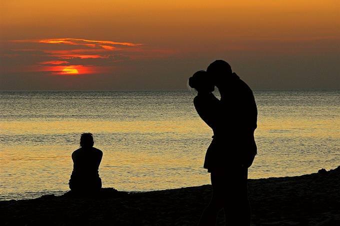 shadows of woman looking at a couple kissing