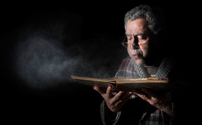 man blowing dust off old book