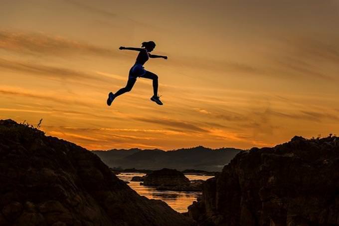 A woman jumping between two mountains