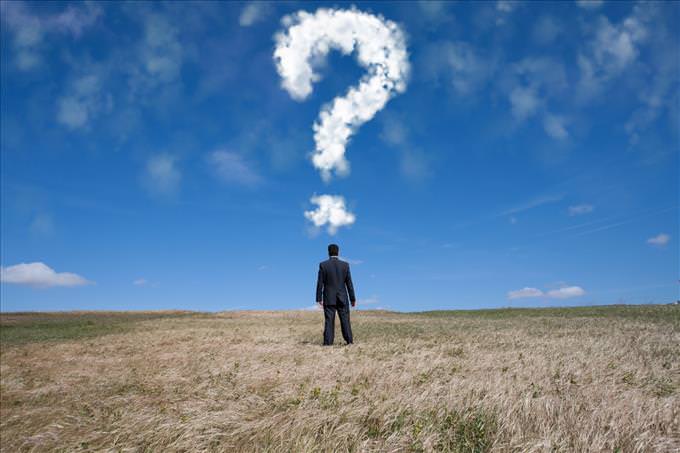 man in field with question mark in clouds
