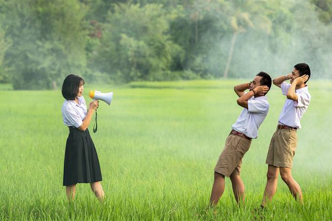 A woman shouting with a megaphone at two men