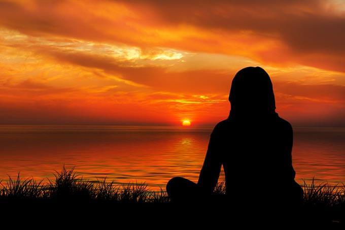 Silhouette of a woman meditating in front of the sea