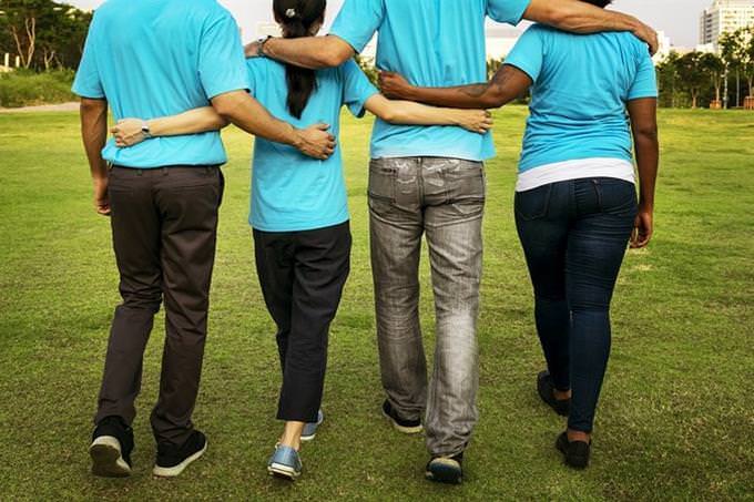 Four people walking together, hugging each other