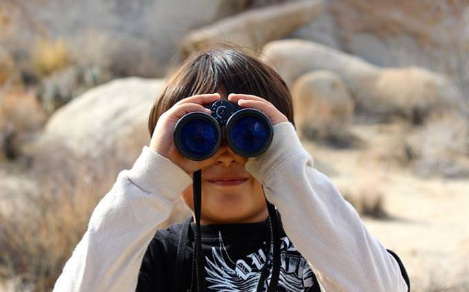 A boy holding binoculars in front of his eyes