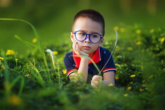 A boy sitting on the grass and looking sad
