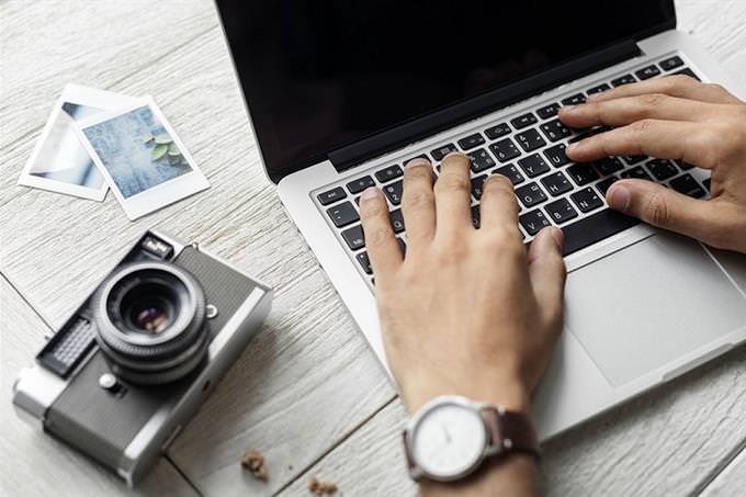 A pair of hands typing on a laptop with a camera