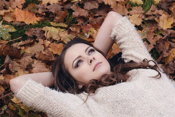 A woman lying on leaves and looking thoughtful