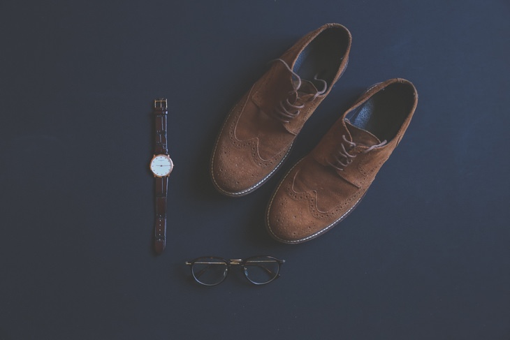 brown suede mens shoes, a clock and glasses on a black background
