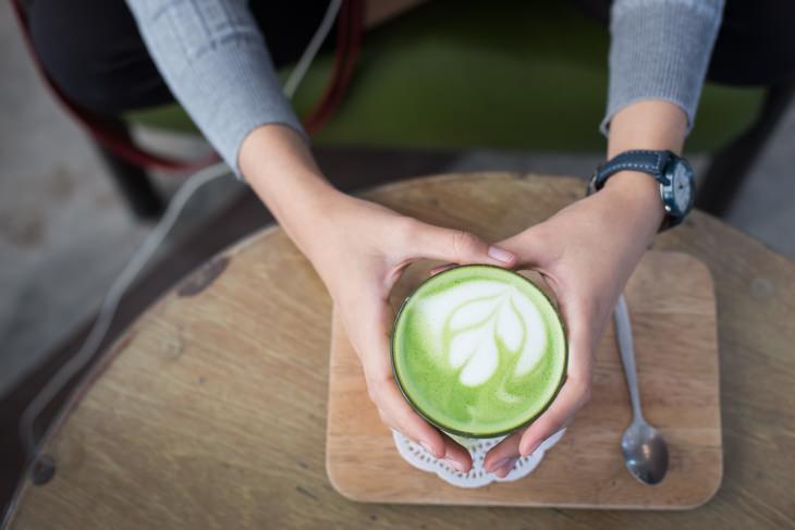 a woman holding a cup of matcha latte