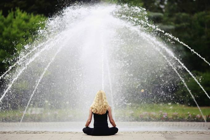 A woman meditating in front of a fountain