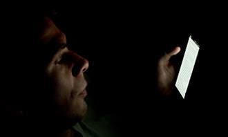 a man looking at his cellphone in the dark