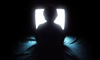 a kid sitting in front of a t.v in the dark