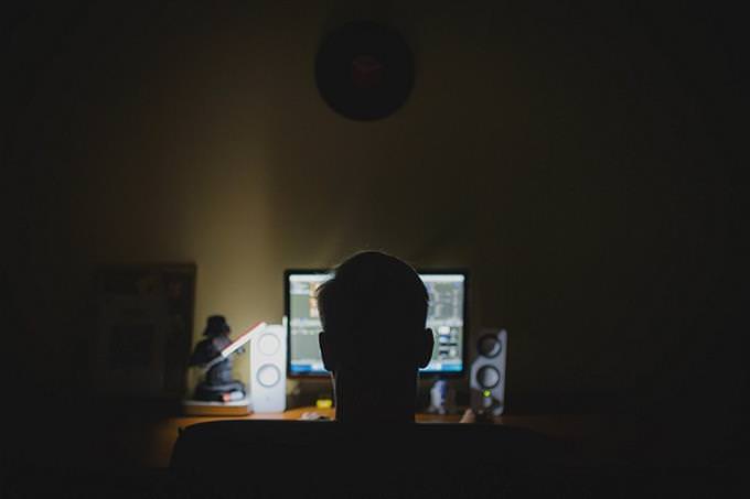 A man sitting in front of a computer screen in the dark