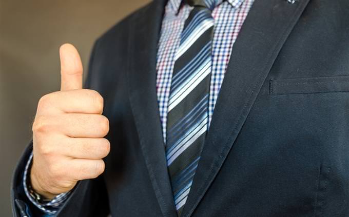 A man in a suit holding up a thumbs up