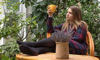 A woman sitting in the garden with a cup of coffee