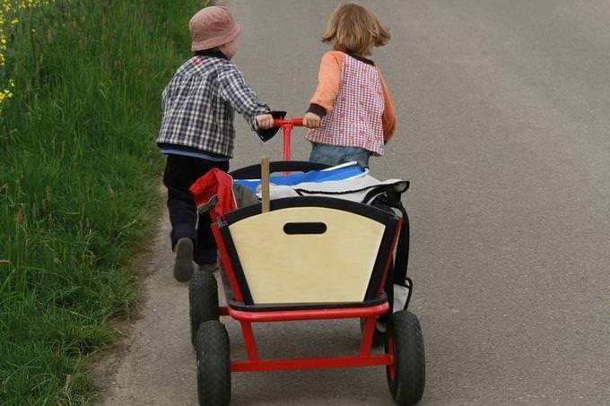 Two children carrying a wagon