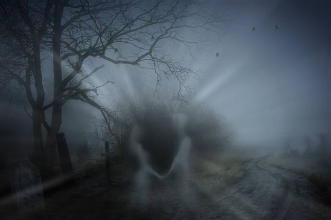 Figures of ghosts against the backdrop of a cemetery at night