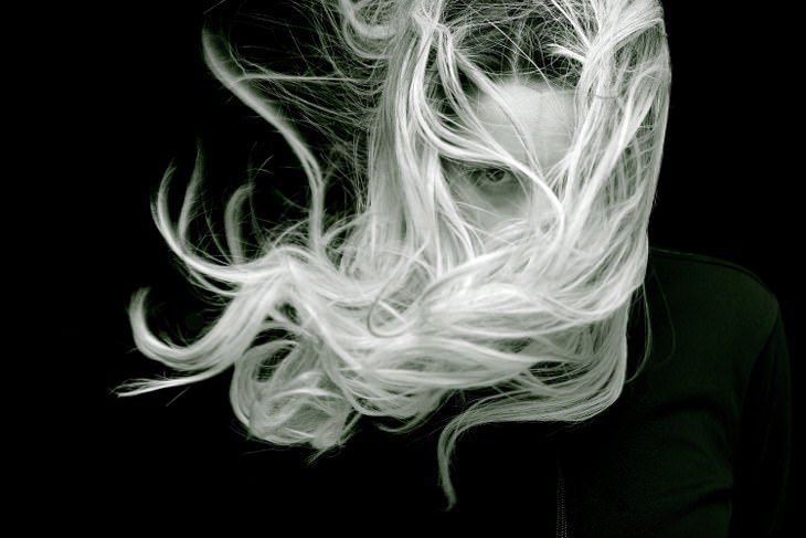 blond women with long hair hiding her fact with black background