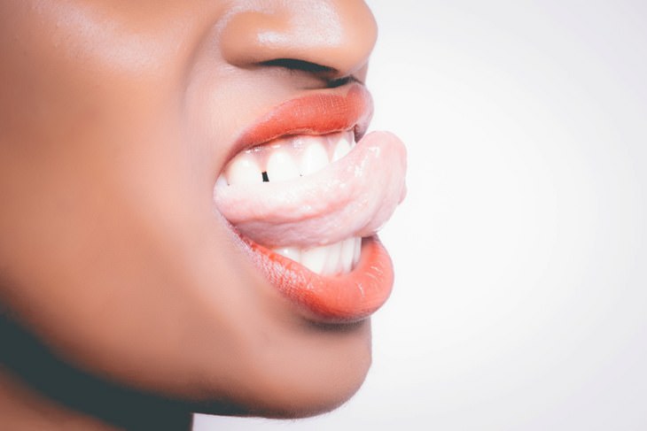 human body facts: woman sticking out tongue and biting down on it