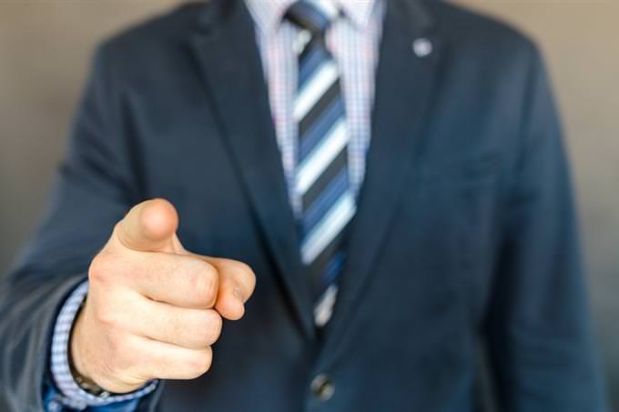 A man in a suit pointing toward the camera