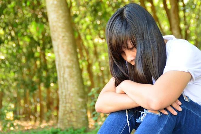 A woman sitting on the ground with her head down