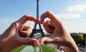 Fingers create a heart shape against the backdrop of the Eiffel Tower in Paris