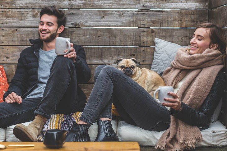 happy couple with a pug - human psychology meaning