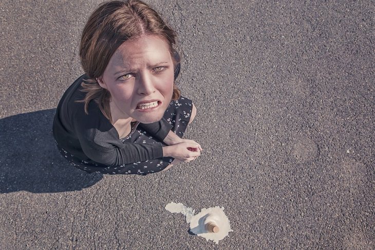 girl crouched down looking sad about the ice cream cone on the floor