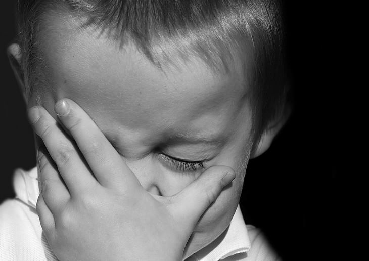 boy covering his face with his hand