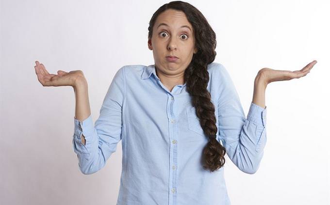 A woman raises her hands as a sign of confusion