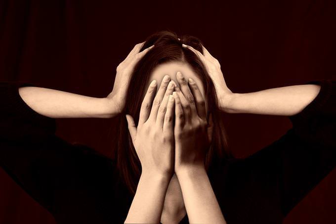 A woman hiding her face and ears with 4 hands