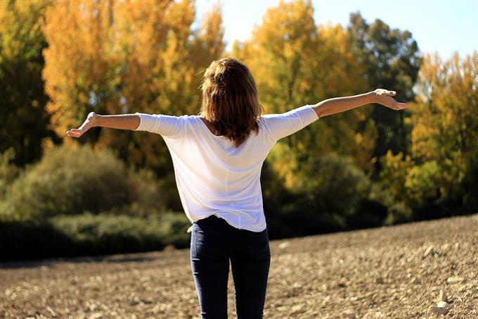 A woman looking at nature with her hands spread out