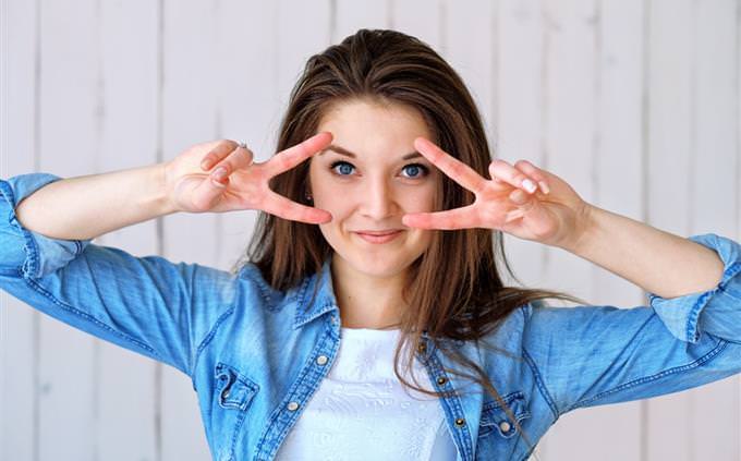 A woman holding up peace signs by her eyes