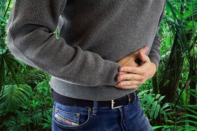 A man in the jungle holding his stomach