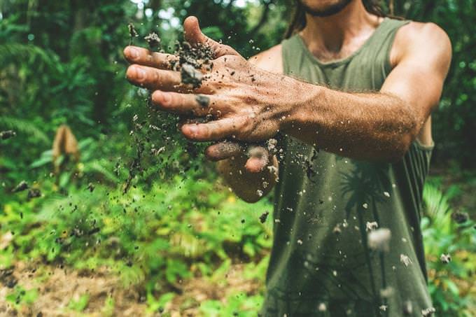 A man rubbing his hands with dirt