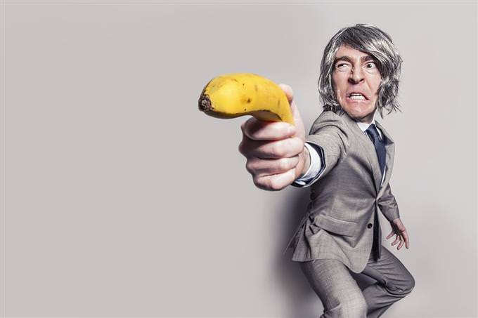 A man aiming a banana like a gun
