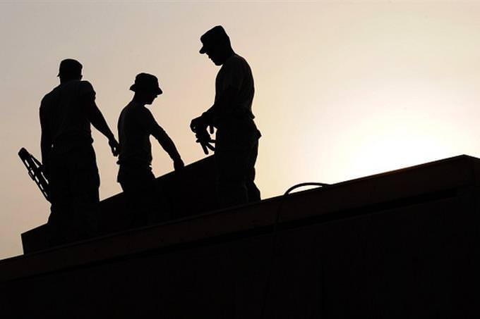 People standing on a building in front of the sun