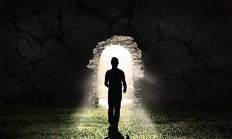 A man standing in front of the light at the end of a tunnel