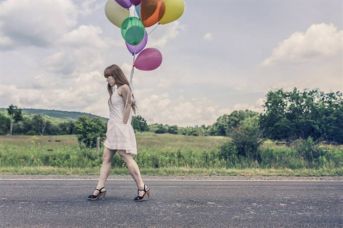 A sad woman holding colored balloons