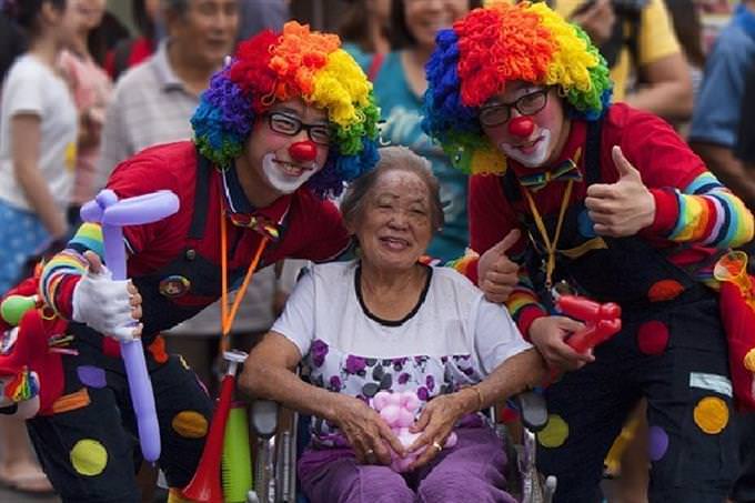 Two clowns making an older woman happy