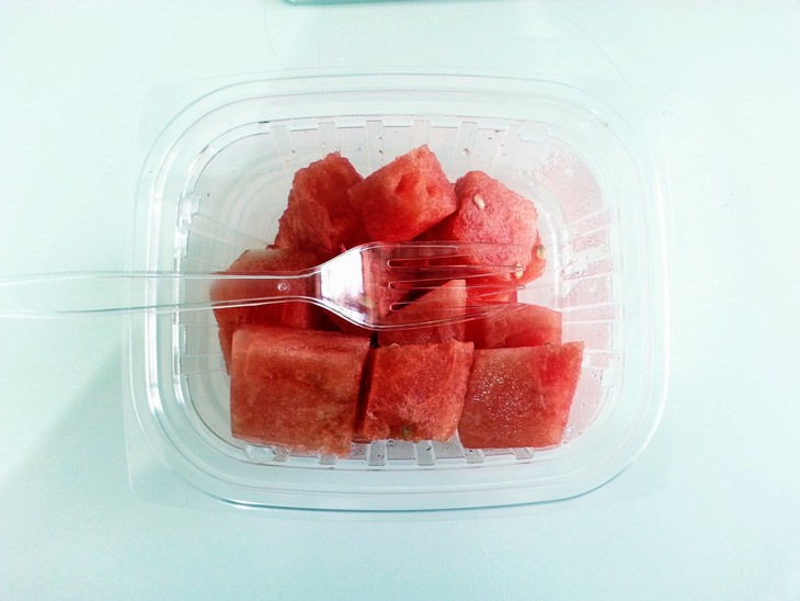 watermelon pieces in a plastic container and a plastic fork