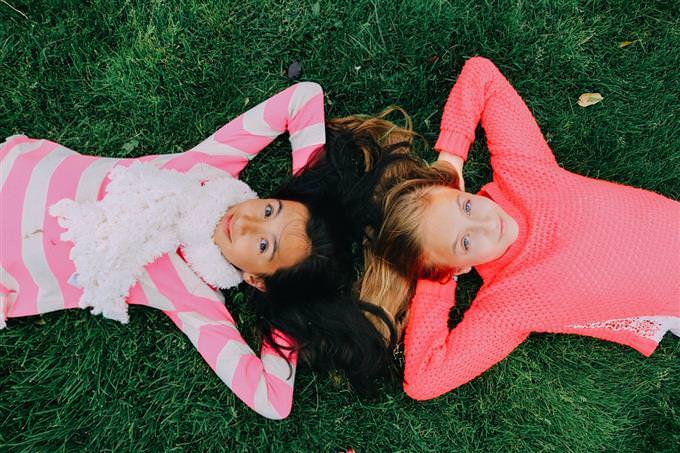 Two girls lying head to head on the grass