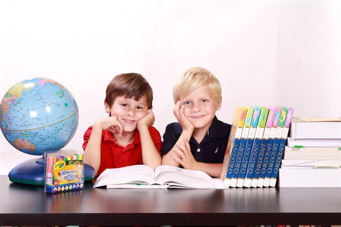 Children sitting at a table surrounded by a globe and books