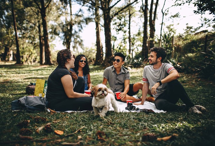 4 people and a dog having a picnic in the park
