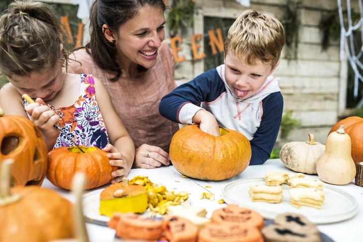 a woman is teaching her children to carve out pumpkins